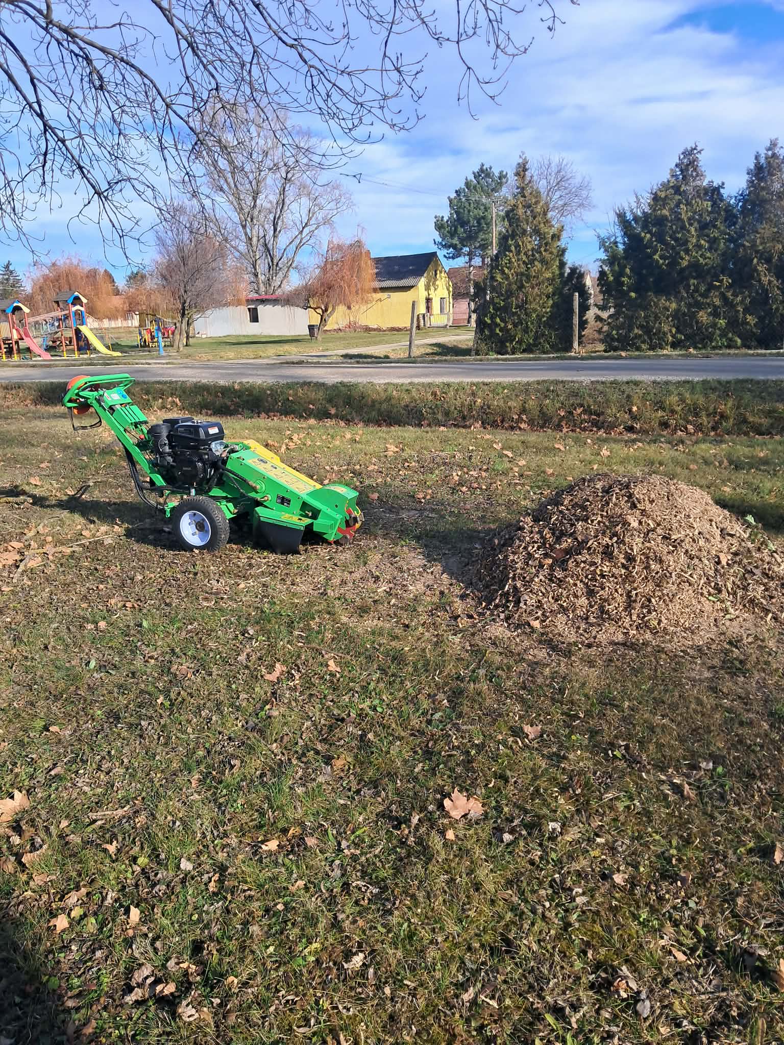 Tuskómarás — zöld marógép őszi parkban, faforgács kúppal